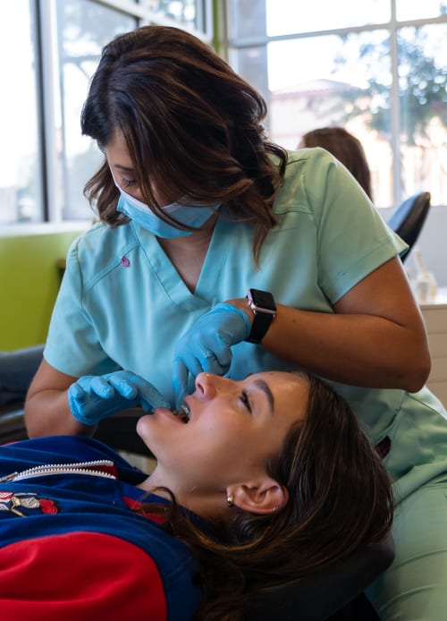 Duong Orthodontics's Clinical Assistant working on a young patient's mouth.